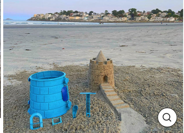 Sandcastle with blue mold on a beach with ocean and houses in the background